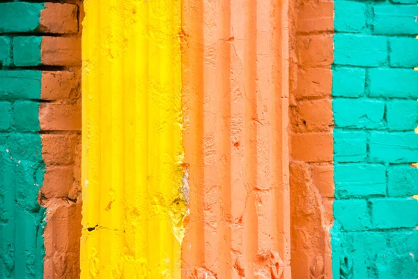 Vermelho, laranja, amarelo e azul combinação de cores parede de dano texturizado velho com tijolos coloridos . — Fotografia de Stock