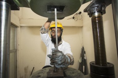 Bangladeş 20 Mayıs 2015: Çelik çubuk dayanıklılık testi makinesi kullanan bir fabrika laboratuvar operatörü
