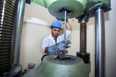 Bangladeş 20 Mayıs 2015: Çelik çubuk dayanıklılık testi makinesi kullanan bir fabrika laboratuvar operatörü