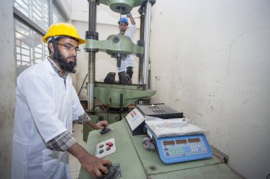 Bangladeş 20 Mayıs 2015: Çelik çubuk dayanıklılık testi makinesi kullanan bir fabrika laboratuvar operatörü