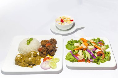 Asya tarzı ramazan sehri yemek seti. Sağlıklı bir yemek. Bir tabak yeşil salata, bir tabak uçak pirinci ve beyaz arka planda Faluda Dessart soslu iki çeşit körili biftek..