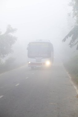 Bangladeş 06 Ocak 2014: Sisli bir kış sabahı, sisli sokaklardan bir otobüs geçiyor ve Ranisankail, Thakurgaon 'da trafiği yavaşlatıyor.