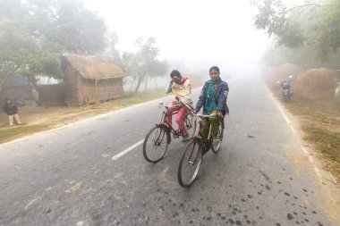 Bangladeş 06 Ocak 2014: Sisli bir kış sabahı, iki genç kız bisiklete binerek okula gidiyor. Ranisankail, Thakurgaon 'da..