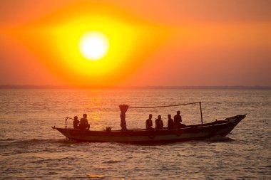 Denizde Renkli Altın Gün Batımı. Balıkçılar, gün batımında Chandpur, Bangladeş 'teki Char Samarj plajında elle eve balıklarla dönüyorlar..