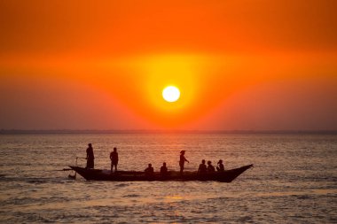Denizde Renkli Altın Gün Batımı. Balıkçılar, gün batımında Chandpur, Bangladeş 'teki Char Samarj plajında elle eve balıklarla dönüyorlar..