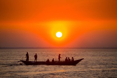Denizde Renkli Altın Gün Batımı. Balıkçılar, gün batımında Chandpur, Bangladeş 'teki Char Samarj plajında elle eve balıklarla dönüyorlar..