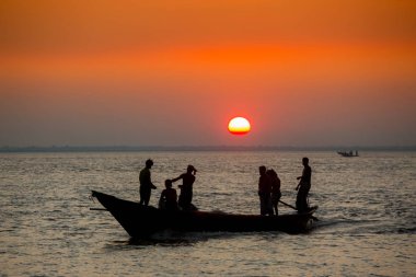 Denizde Renkli Altın Gün Batımı. Balıkçılar, gün batımında Chandpur, Bangladeş 'teki Char Samarj plajında elle eve balıklarla dönüyorlar..