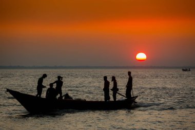 Denizde Renkli Altın Gün Batımı. Balıkçılar, gün batımında Chandpur, Bangladeş 'teki Char Samarj plajında elle eve balıklarla dönüyorlar..