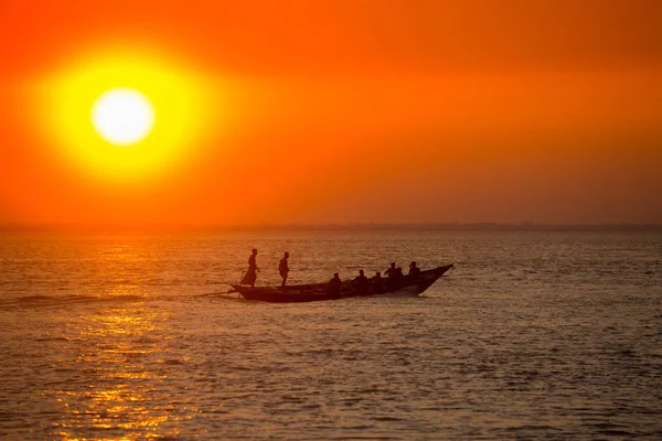 Coucher de soleil doré coloré sur la mer. Les pêcheurs rentrent chez eux avec des poissons, manuellement au coucher du soleil sur la plage de Char Samarj à Chandpur, Bangladesh . — Photo