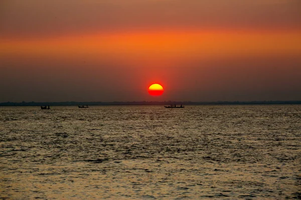 海の上のカラフルな黄金の夕日。バングラデシュのチャンプールにあるチャール・サマルジ・ビーチでは、日没時に漁師たちが魚と一緒に帰宅しています。. — ストック写真
