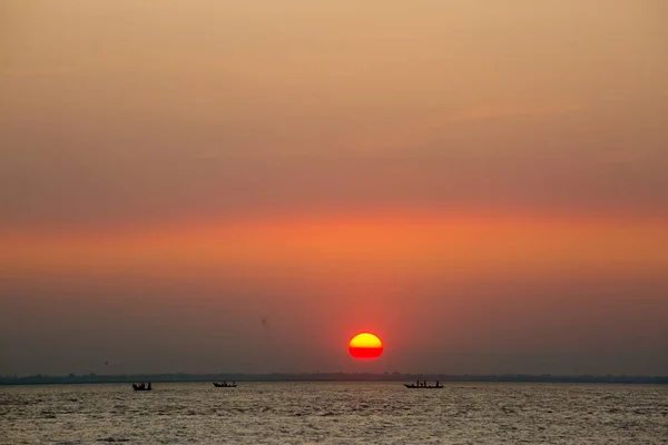 海の上のカラフルな黄金の夕日。バングラデシュのチャンプールにあるチャール・サマルジ・ビーチでは、日没時に漁師たちが魚と一緒に帰宅しています。. — ストック写真