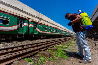 Bir çalışan, Dhaka Kamalapur Tren İstasyonu 'ndaki yeni bir koronavirüse karşı önlem olarak trenin dışına dezenfektan sıkar. Bangladeş 30 Mart 2020