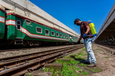 Bir çalışan, Dhaka Kamalapur Tren İstasyonu 'ndaki yeni bir koronavirüse karşı önlem olarak trenin dışına dezenfektan sıkar. Bangladeş 30 Mart 2020