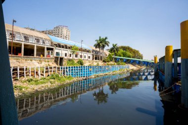 Mavi gökyüzü Sadarghat Fırlatma Terminali 'nin siyah suyuna yansıyor. Bangladeş 30 Mart 2020