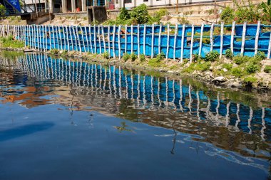 Mavi gökyüzü Sadarghat Fırlatma Terminali 'nin siyah suyuna yansıyor. Bangladeş 30 Mart 2020