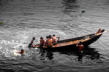 Dünya halkı esir alındığında Coronavirus, Dhaka 'da bazı çocuklar Buriganga Nehri' nin siyah kirli sularında oynuyorlar. Bangladeş 30 Mart 2020