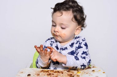 Bir yaşındaki çocuk şut pasta bir dilim kirli elde tek başına yemek.