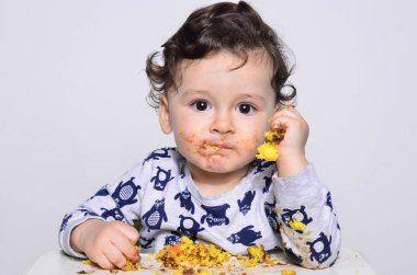 Bir yaşındaki çocuk şut pasta bir dilim kirli elde tek başına yemek.