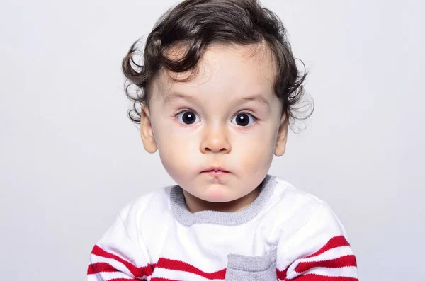 Portrait of a cute curly hair baby boy looking surprised. — Stock Photo, Image