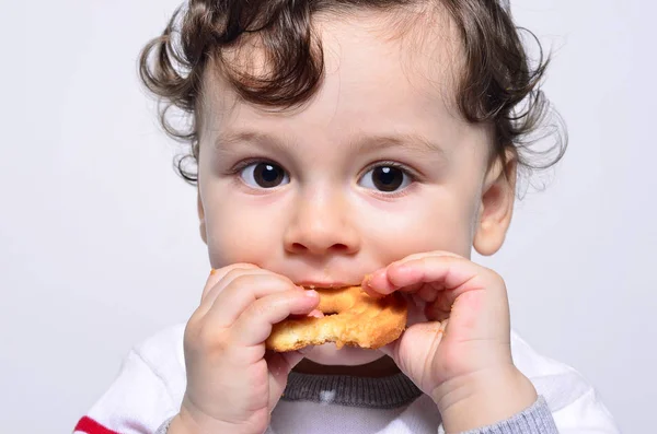 Retrato de um bebê bonito comendo um biscoito . — Fotografia de Stock