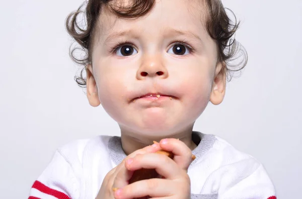 Portrait d'un bébé mignon mangeant un biscuit faisant un drôle de visage . — Photo