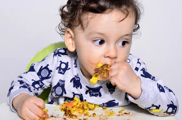 Un bambino di un anno che mangia una fetta di torta di compleanno da solo si sporca . — Foto Stock