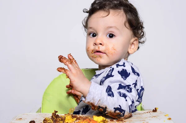 Bir yaşındaki çocuk şut pasta bir dilim kirli elde tek başına yemek.