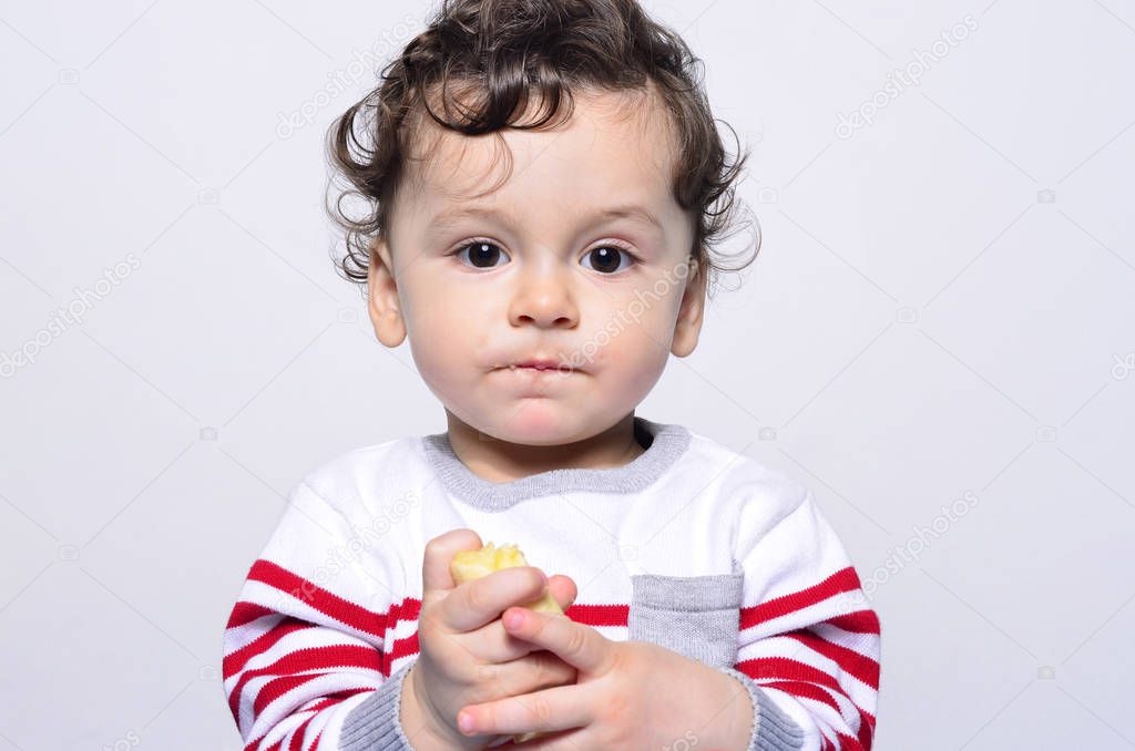 Portrait of a cute baby eating a banana.