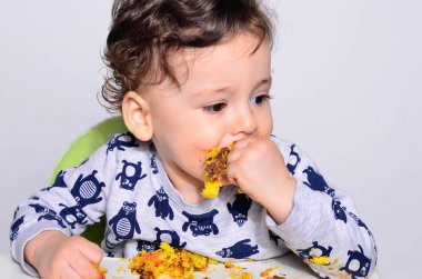 Bir yaşındaki çocuk şut pasta bir dilim başına yemek.