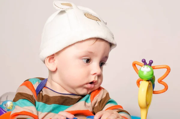 Junge mit süßem Hut sitzt und spielt mit Spielzeug. — Stockfoto
