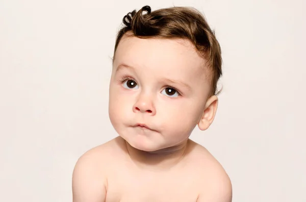 Portrait of a cute baby boy looking up cringing making a funny  face lifting his eyebrow wondering. — Stock Photo, Image
