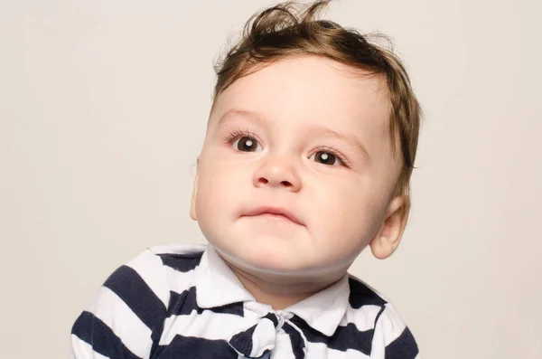 Portrait of a cute baby boy looking up making a funny face lifting his eyebrow wondering. — Stock Photo, Image