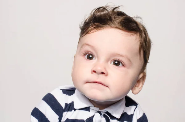 Portrait of a cute baby boy looking up making a funny face lifting his eyebrow wondering. — Stock Photo, Image