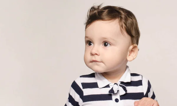 Porträtt av en söt baby pojke tittar bort nyfikna med hans stora ögon. — Stockfoto