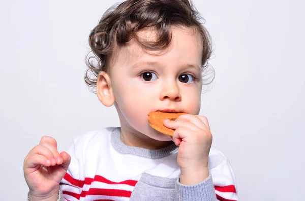 Retrato de un bebé lindo comiendo una galleta . — Foto de Stock