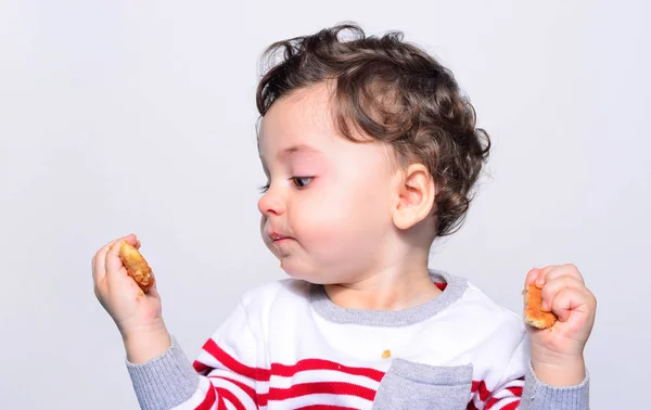 Retrato de um bebê bonito comendo um biscoito . — Fotografia de Stock