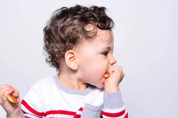 Retrato de un bebé lindo comiendo una galleta . — Foto de Stock