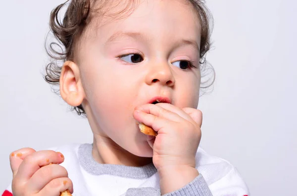 Retrato de un bebé lindo comiendo una galleta . — Foto de Stock