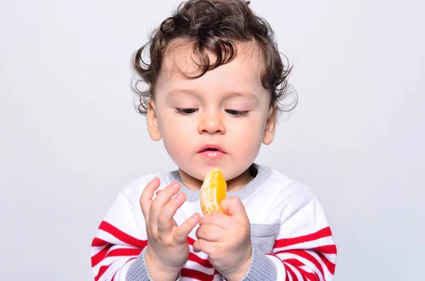 Retrato de un lindo bebé comiendo naranja . — Foto de Stock