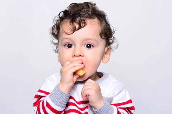 Retrato de um bebê bonito comendo laranja . — Fotografia de Stock