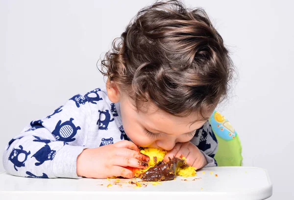一岁的孩子独自吃一片粉碎的生日蛋糕. — 图库照片