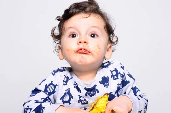 Un bambino di un anno che mangia una fetta di torta di compleanno da solo . — Foto Stock