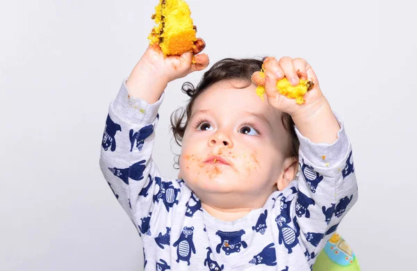 Un bambino di un anno che mangia una fetta di torta di compleanno da solo . — Foto Stock