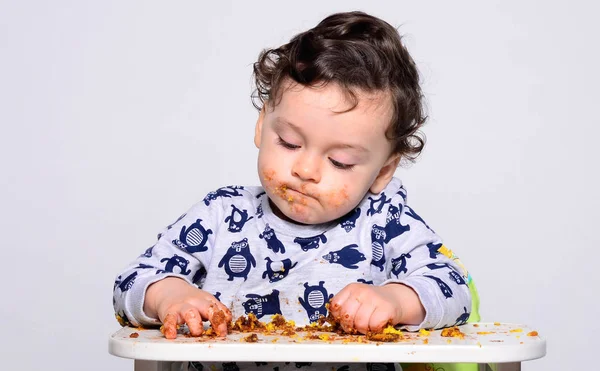 Un bambino di un anno che mangia una fetta di torta di compleanno da solo . — Foto Stock