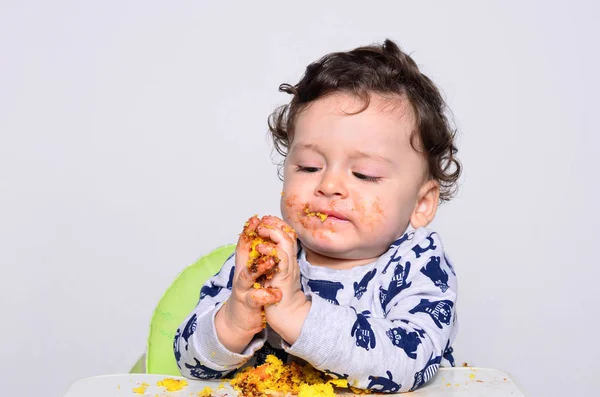 1 歳の子供が自分でスマッシュの誕生日ケーキのスライスを食べる. ストック画像