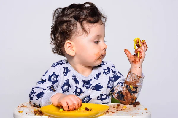 Bir yaşındaki çocuk şut pasta bir dilim başına yemek. Telifsiz Stok Imajlar