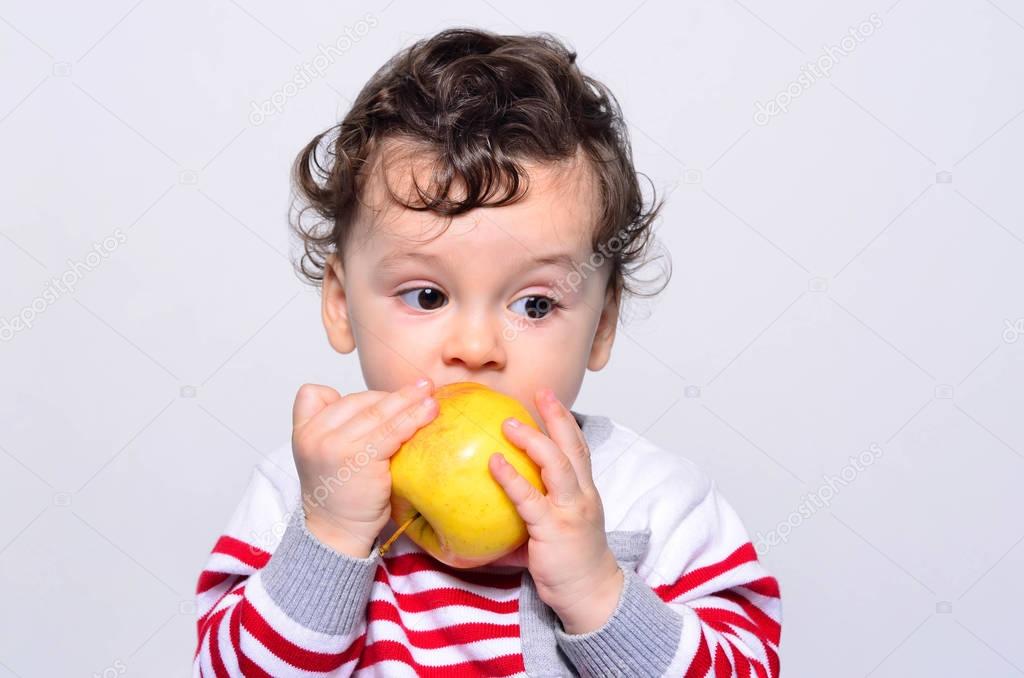 Portrait of a cute baby eating an apple. 