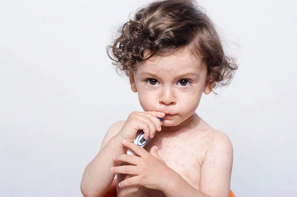 Portrait of a cute sick baby boy with fever holding a thermometer. — Stock Photo, Image