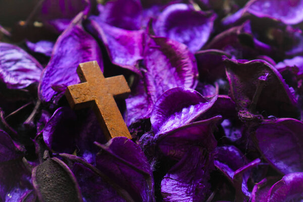 Vintage wooden crucifix cross on dried purple flowers. Purple is symbolic color of Lent.