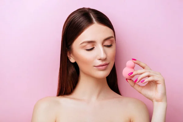 Menina engraçada segurando esponja rosa perto de seu rosto. Retrato de menina no fundo rosa . — Fotografia de Stock